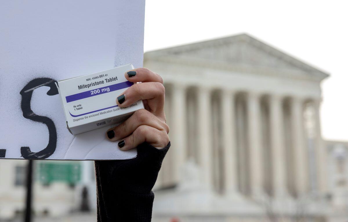 An abortion- rights activist holds a box of mifepristone pills as demonstrators from both anti-abortion and abortion-rights groups rally outside the Supreme Court in Washington, Tuesday, March 26, 2024. (AP Photo/Amanda Andrade-Rhoades, File)