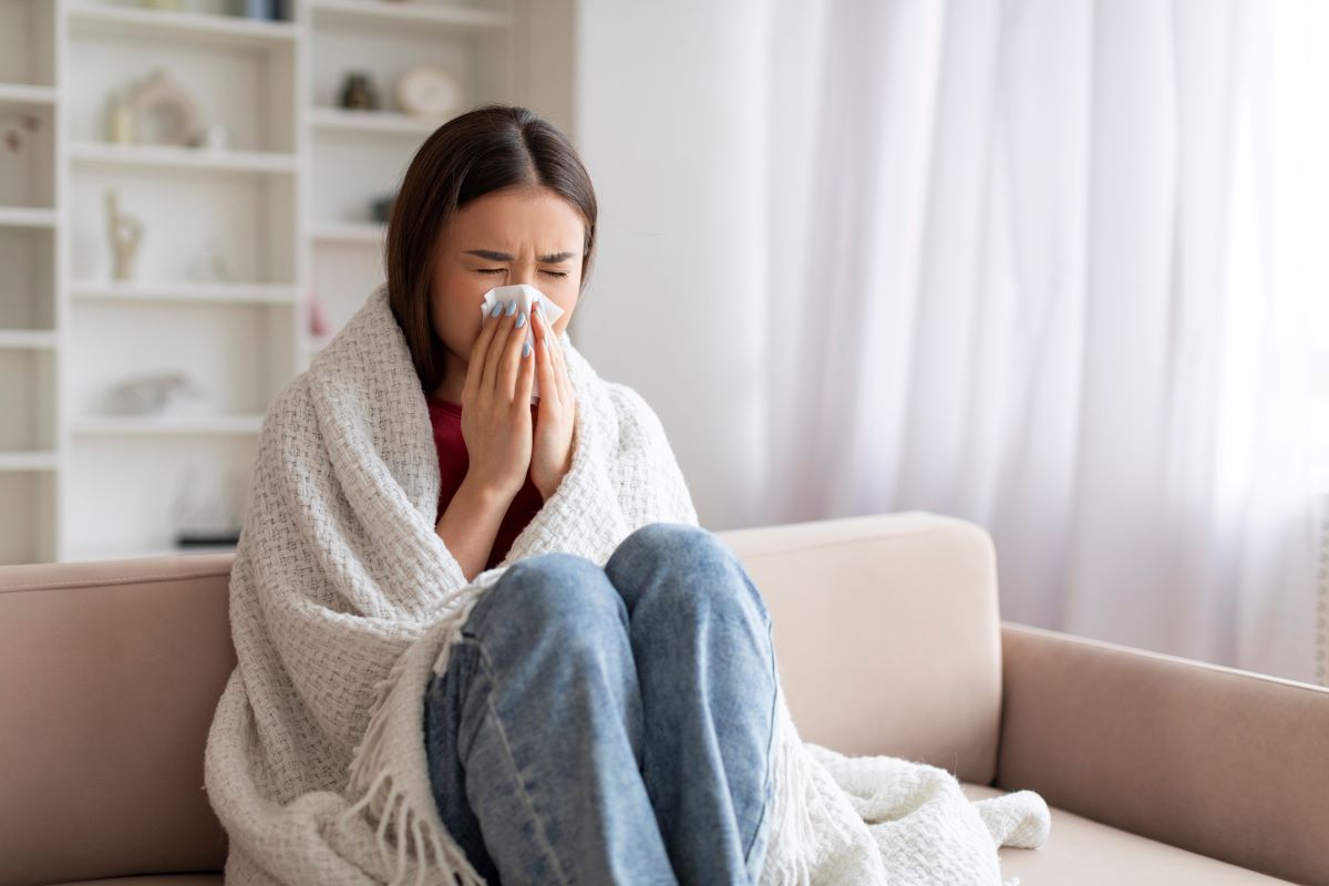 Woman on couch blowing nose