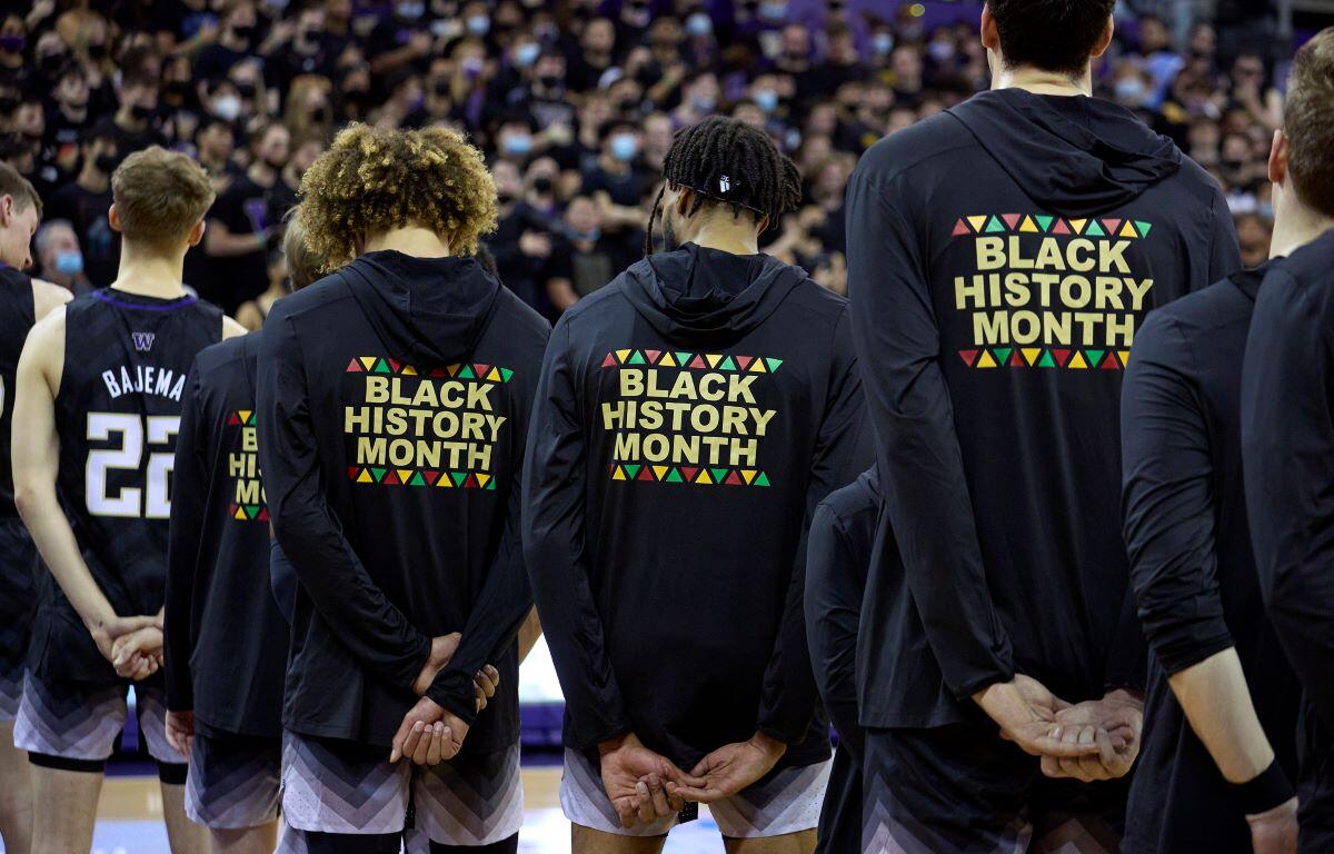 Washington players stand during the playing of the national anthem wearing warm-up jackets for Black History Month before an NCAA college basketball game against Arizona, Feb. 12, 2022, in Seattle. (AP Photo/John Froschauer, File)