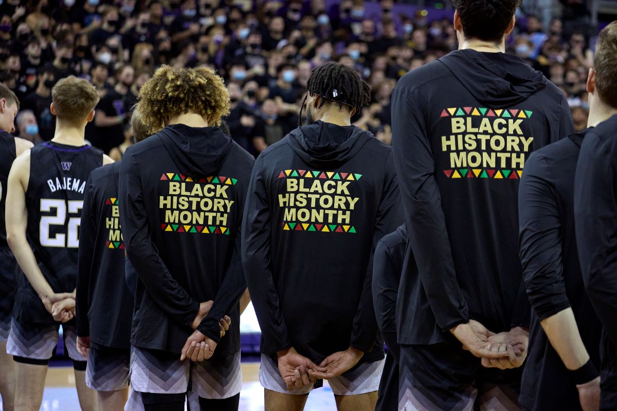 Washington players stand during the playing of the national anthem wearing warm-up jackets for Black History Month before an NCAA college basketball game against Arizona, Feb. 12, 2022, in Seattle. (AP Photo/John Froschauer, File)
