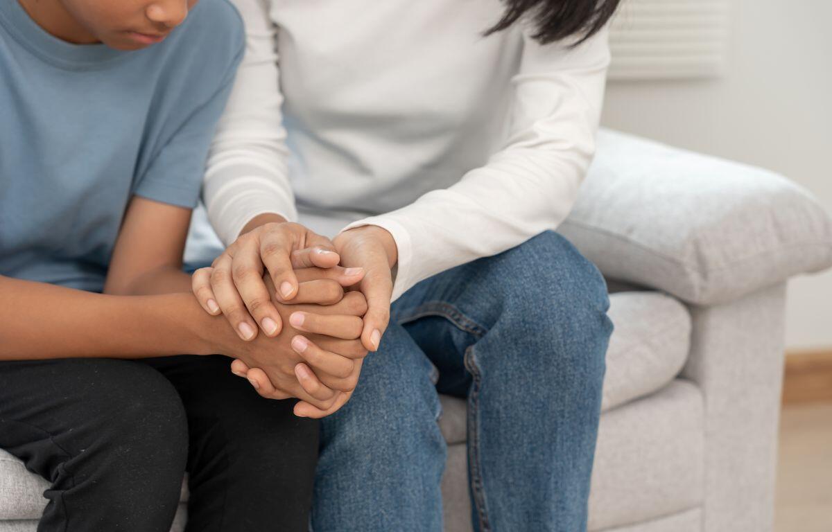 Mother holding son's hand - experiencing mental health crisis