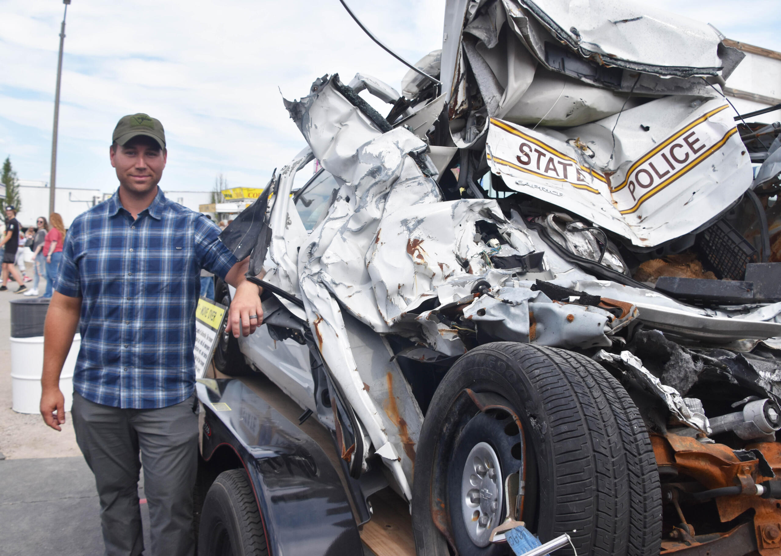 Trooper Alex Womack stands beside his wrecked squad. Womack sustained arm, leg and back injuries and required more than a year off work to recover. Courtesy Illinois State Police)