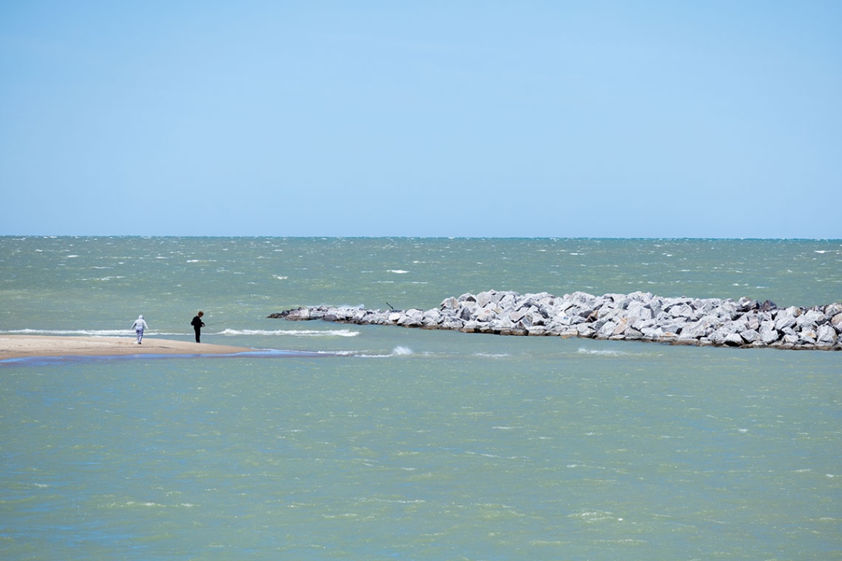 Two people fish on a beach at Illinois Beach State Park near one of 22 breakwaters which protect the shoreline from erosion. (Capitol News Illinois photo by Andrew Adams)