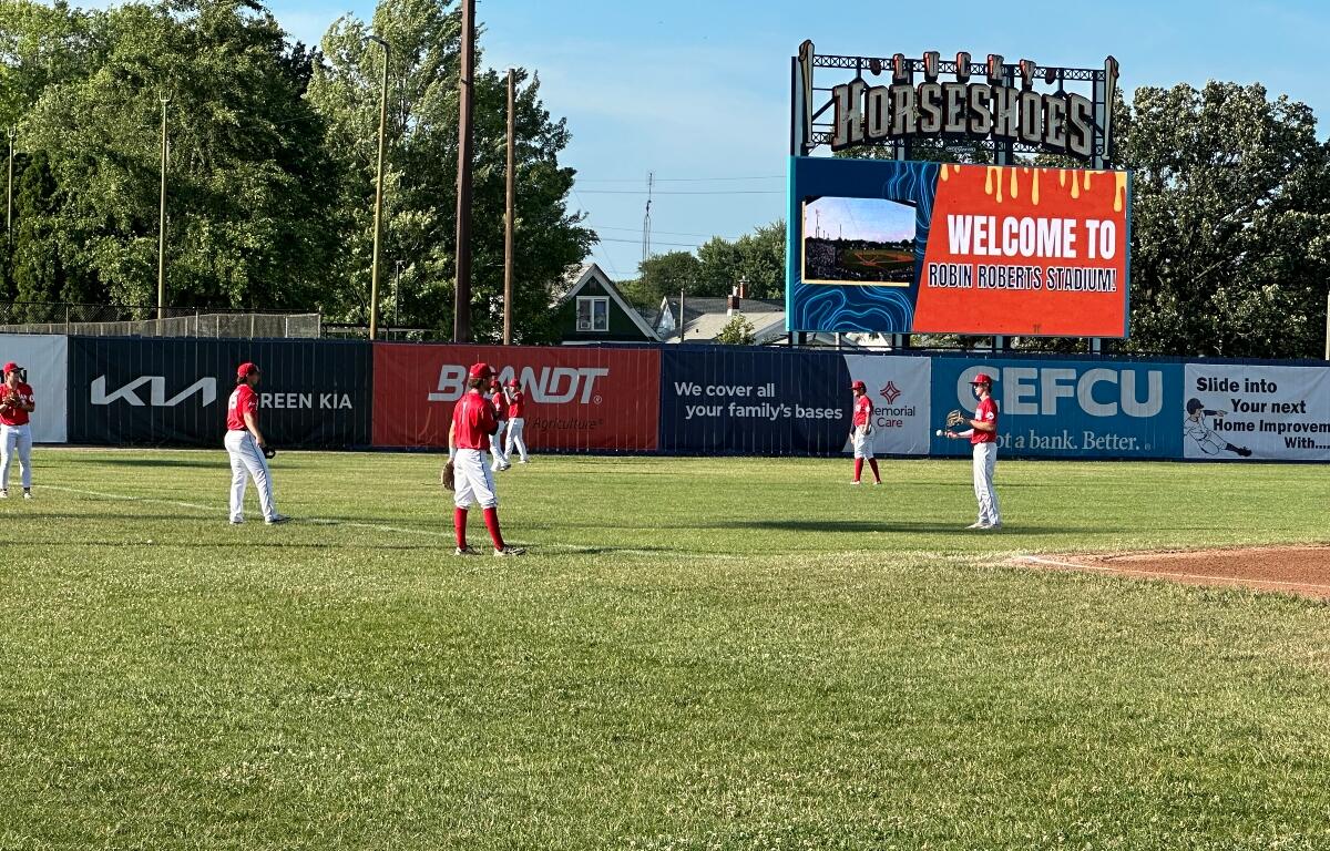 Springfield Lucky Horseshoes players warm up in the outfield on a hot day.