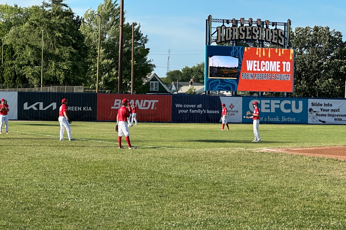 Springfield Lucky Horseshoes players warm up in the outfield on a hot day.
