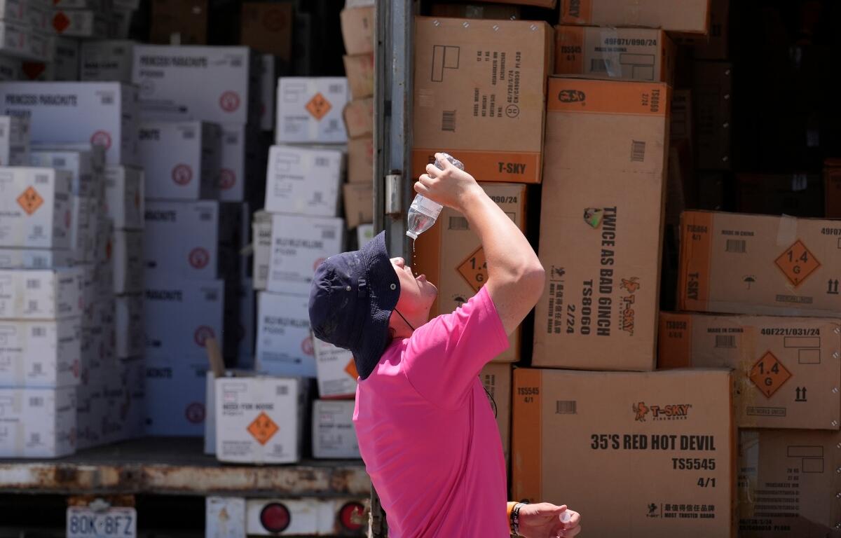 FILE - Wyatt Seymore pours the last drops of liquid from a water bottle into his mouth as he takes a break from unloading a stiflingly hot trailer of fireworks outside Powder Monkey Fireworks ahead of the opening of the stand, June 17, 2024, in Weldon Spring, Mo. (AP Photo/Jeff Roberson, File)