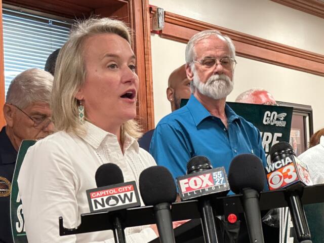 Springfield resident Bob Croteau, in blue, stands near Rep. Nikki Budzinski (D-Springfield) at a news conference at the AFL-CIO headquarters in downtown Springfield Aug. 21, 2025. Crouteau was one of a number of AFSCME union members who surrounded the Congresswoman.