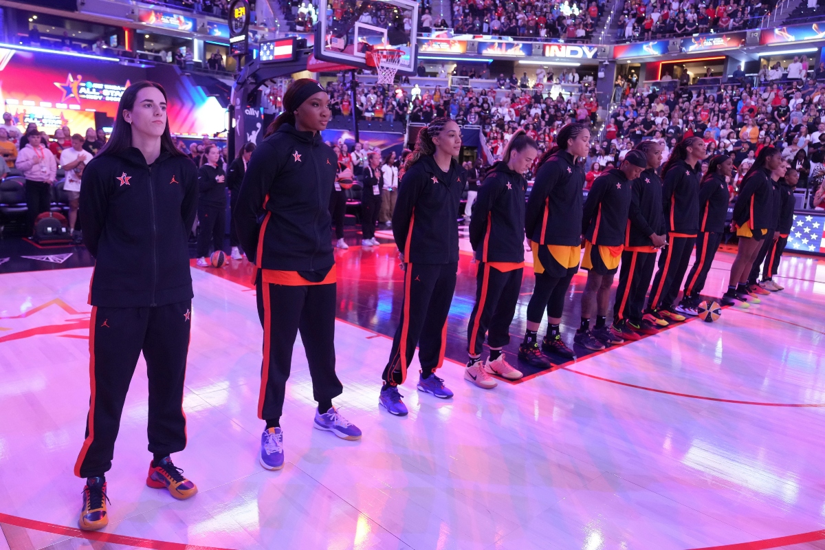 Indiana Fever's Caitlin Clark, left, stands with Team Clark during the national anthem before the WNBA All-Star basketball game, Saturday, July 19, 2025, in Indianapolis. (AP Photo/Michael Conroy)