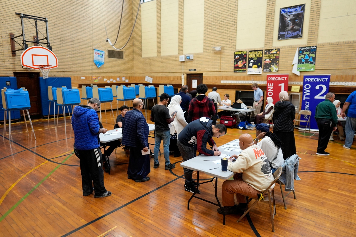 FILE - Voters wait to receive their ballots at a polling place at McDonald Elementary School, Nov. 5, 2024, in Dearborn, Mich. (AP Photo/Charlie Neibergall, File)