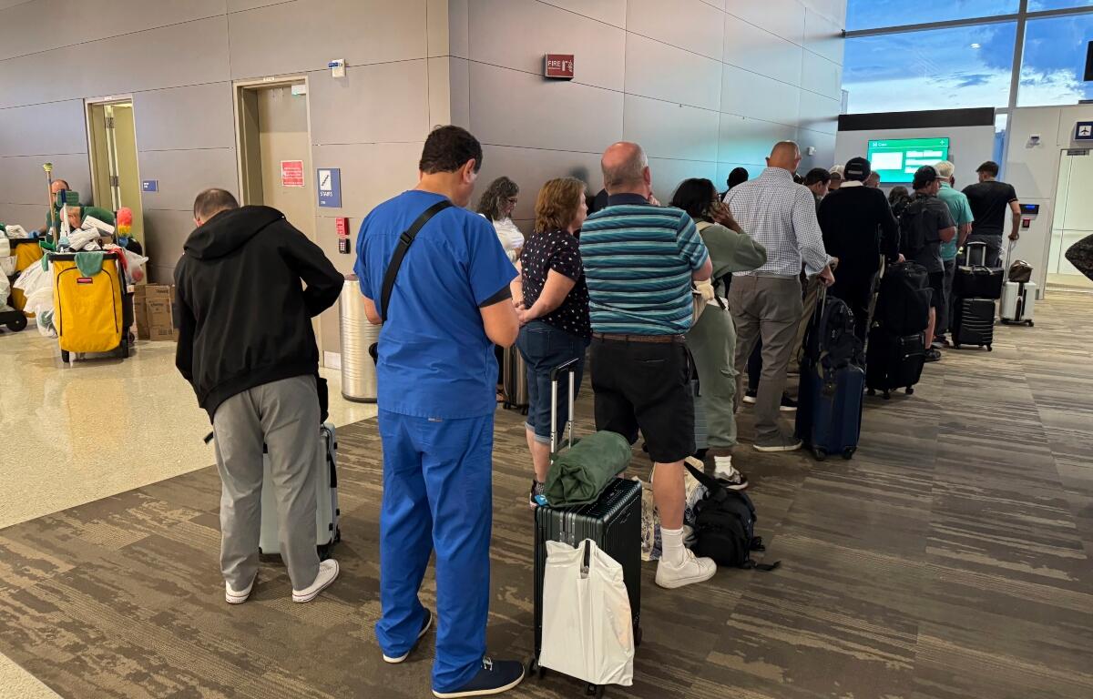 Passengers seeks updates on their delayed flight at Louis Armstrong New Orleans International Airport, Wednesday, Aug. 6, 2025, in Kenner, La. (AP Photo/Jack Brooks)
