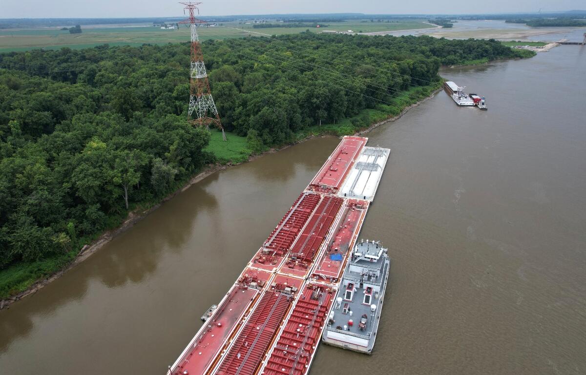 A blue tarp covers the wreckage of a helicopter after it clipped a power line spanning the Mississippi River and crashed onto a barge Thursday, Aug. 7, 2025, in East Alton, Ill. (AP Photo/Jeff Roberson)