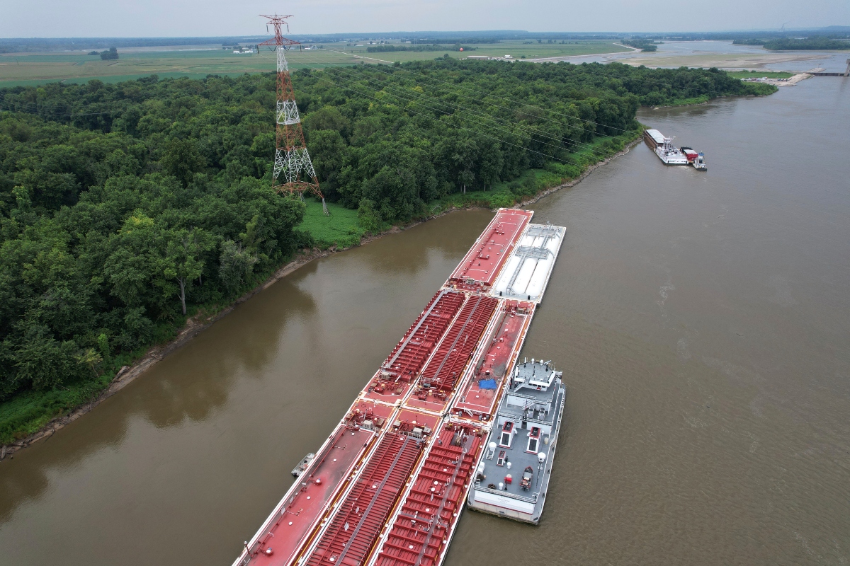 A blue tarp covers the wreckage of a helicopter after it clipped a power line spanning the Mississippi River and crashed onto a barge Thursday, Aug. 7, 2025, in East Alton, Ill. (AP Photo/Jeff Roberson)