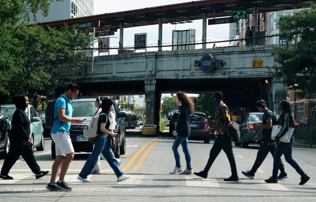 Pedestrians cross a street in front of a CTA station in Chicago, Tuesday, Aug. 26, 2025. (AP Photo/Nam Y. Huh)