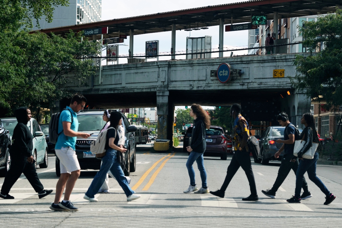 Pedestrians cross a street in front of a CTA station in Chicago, Tuesday, Aug. 26, 2025. (AP Photo/Nam Y. Huh)