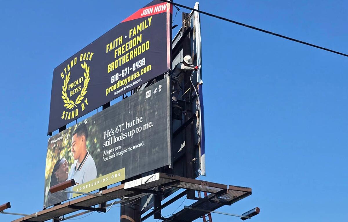 A Lamar Advertising representative on Monday moves an ad for the far-right extremist group Proud Boys; the sign was taken down entirely around noon Tuesday. (Capitol News Illinois photo by Molly Parker)