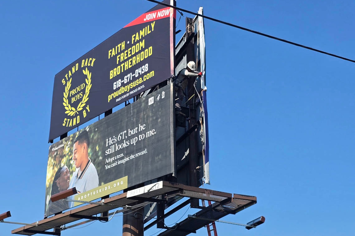 A Lamar Advertising representative on Monday moves an ad for the far-right extremist group Proud Boys; the sign was taken down entirely around noon Tuesday. (Capitol News Illinois photo by Molly Parker)