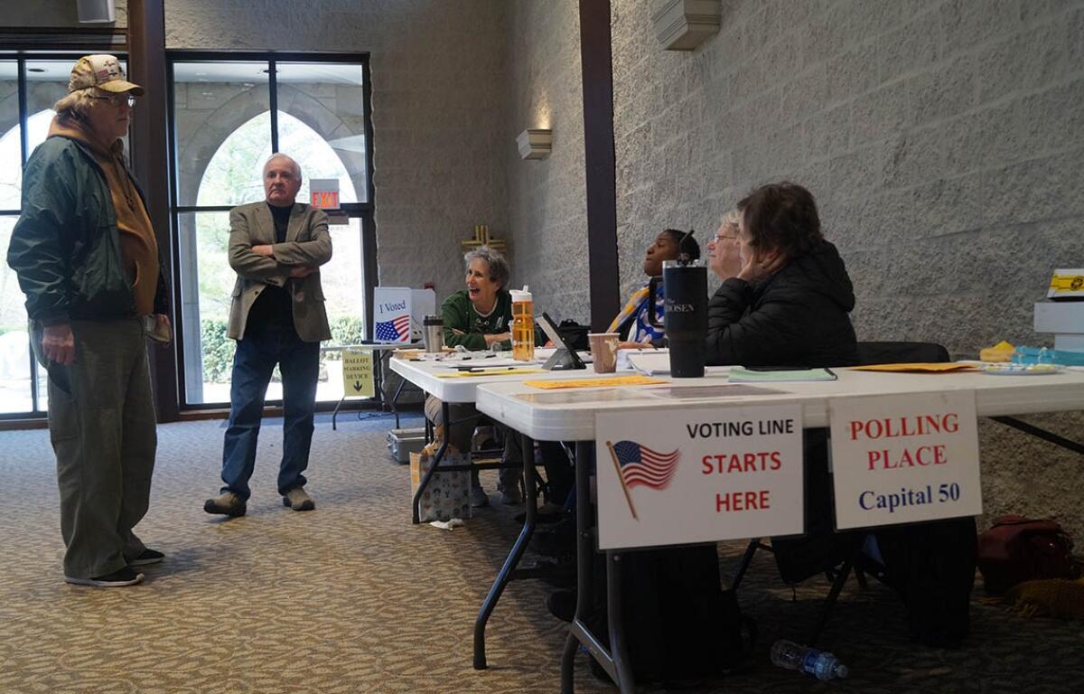 Election workers check voters’ names against a registration list and hand out ballots at a polling place in Springfield. (Capitol News Illinois file photo by Peter Hancock)