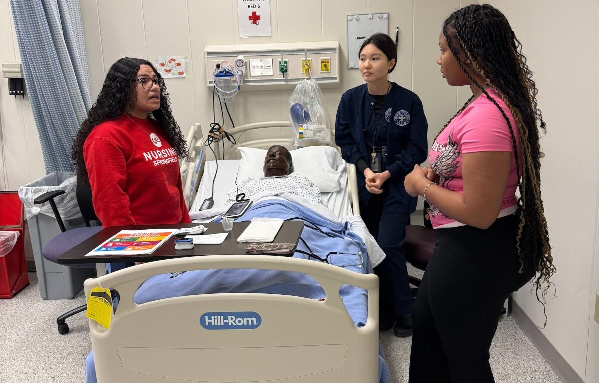 Students in the "Nurse for a Day" program hosted by UIS look over a simulated patient.