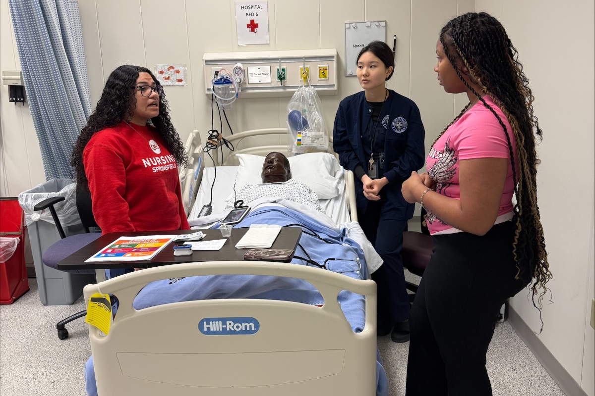 Students in the "Nurse for a Day" program hosted by UIS look over a simulated patient.