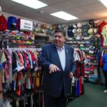 Illinois Gov. J.B. Pritzker visits with members of the family-owned soccer gear business Extreme Soccer, Thursday, Sept. 4, 2025, in Berwyn, Ill. (AP Photo/Erin Hooley)