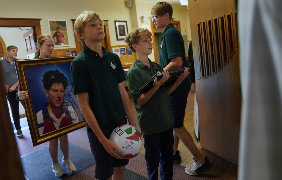 Students of St. John Berchmans' school hold items often linked to Blessed Carlo Acutis, who will be canonized a saint by Pope Leo XIV, before Mass at Blessed Carlo Acutis Parish, on Wednesday, Sept. 3, 2025, in Chicago. (AP Photo/Jessie Wardarski)