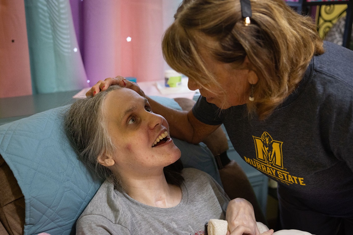 Cortnie Stewart, who suffered a traumatic brain injury in a 1997 car crash, looks up at her mother Judy Stegle at their home in Jonesboro, Illinois. A nearby nonprofit provided respite services to aid in her full-time care before closing as result of the budget impasse. (Julia Rendleman for CNI)