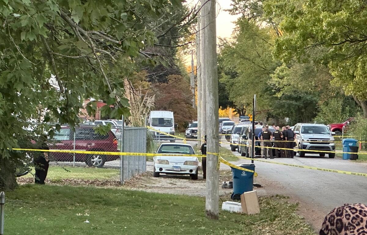 Crime scene tape and law enforcement vehicles are seen on Hoover Avenue October 9, the scene of a triple-homicide.