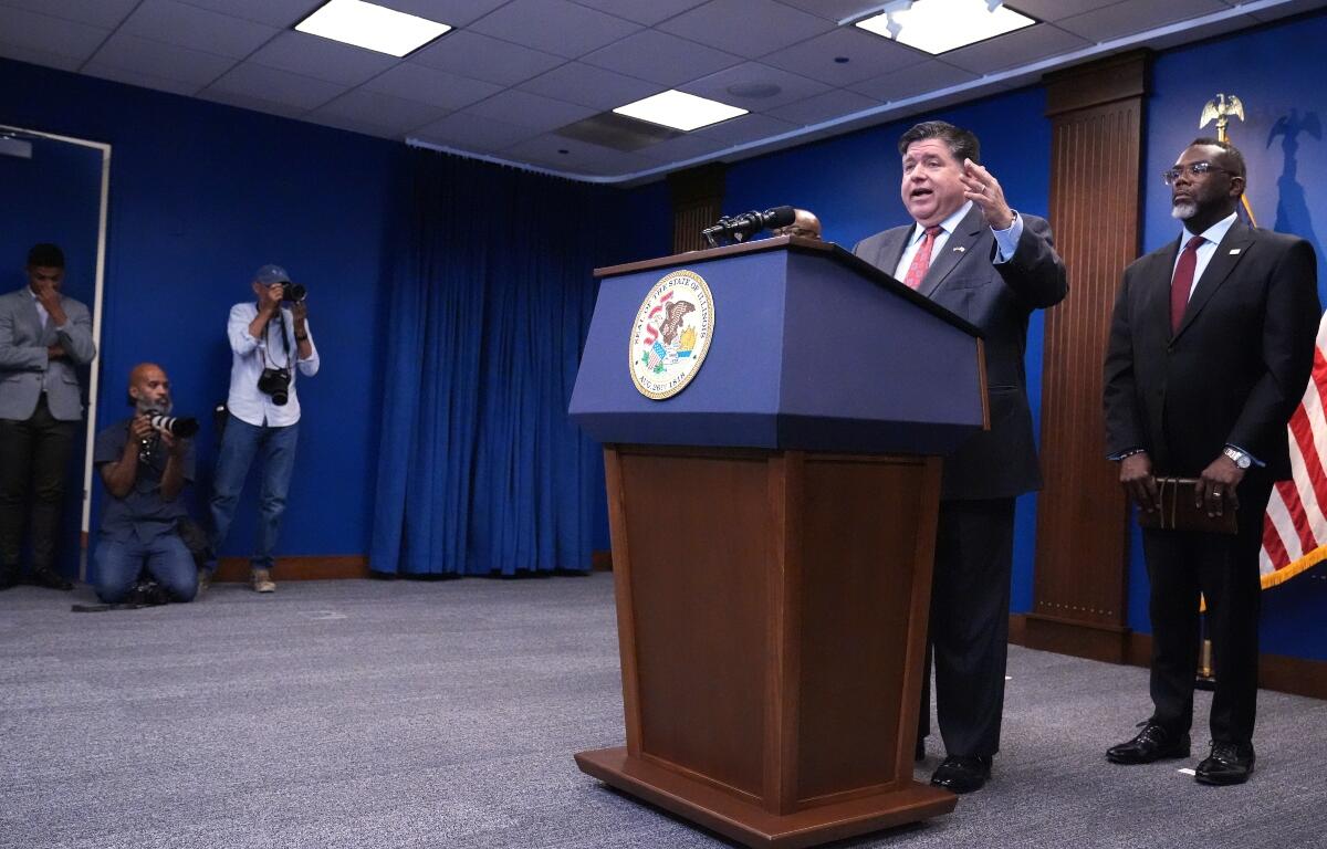 Governor JB Pritzker, second from right, speaks as Chicago Mayor Brandon Johnson, right, listens to him at a news conference in Chicago, Monday, Oct. 6, 2025. (AP Photo/Nam Y. Huh)
