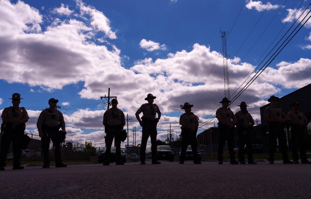 Illinois State Police stand guard as people including members of the Coalition for Spiritual and Public Leadership (CSPL) gather outside a U.S. Immigration and Customs Enforcement facility in Broadview, Ill., Saturday, Oct. 11, 2025. (AP Photo/Adam Gray)