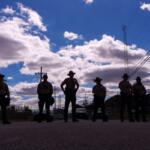 Illinois State Police stand guard as people including members of the Coalition for Spiritual and Public Leadership (CSPL) gather outside a U.S. Immigration and Customs Enforcement facility in Broadview, Ill., Saturday, Oct. 11, 2025. (AP Photo/Adam Gray)