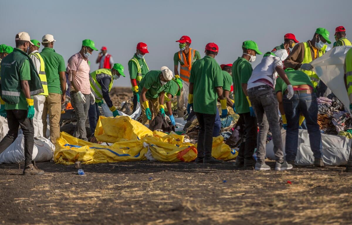 FILE - Workers collect debris on March 12, 2019 at the scene where an Ethiopian Airlines Boeing 737 Max 8 crashed shortly after takeoff, killing all 157 on board, near Bishoftu, or Debre Zeit, south of Addis Ababa, in Ethiopia. (AP Photo/Mulugeta Ayene, File)