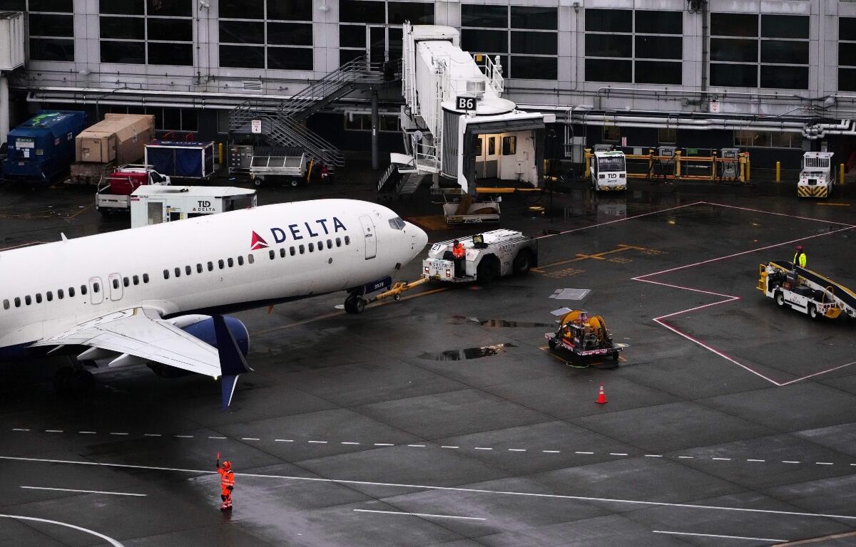 A ground crew worker signals a plane next to a Delta Airlines aircraft at Seattle-Tacoma International Airport, Thursday, Nov. 6, 2025, in SeaTac, Wash. (AP Photo/Lindsey Wasson)