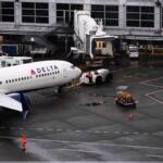 A ground crew worker signals a plane next to a Delta Airlines aircraft at Seattle-Tacoma International Airport, Thursday, Nov. 6, 2025, in SeaTac, Wash. (AP Photo/Lindsey Wasson)