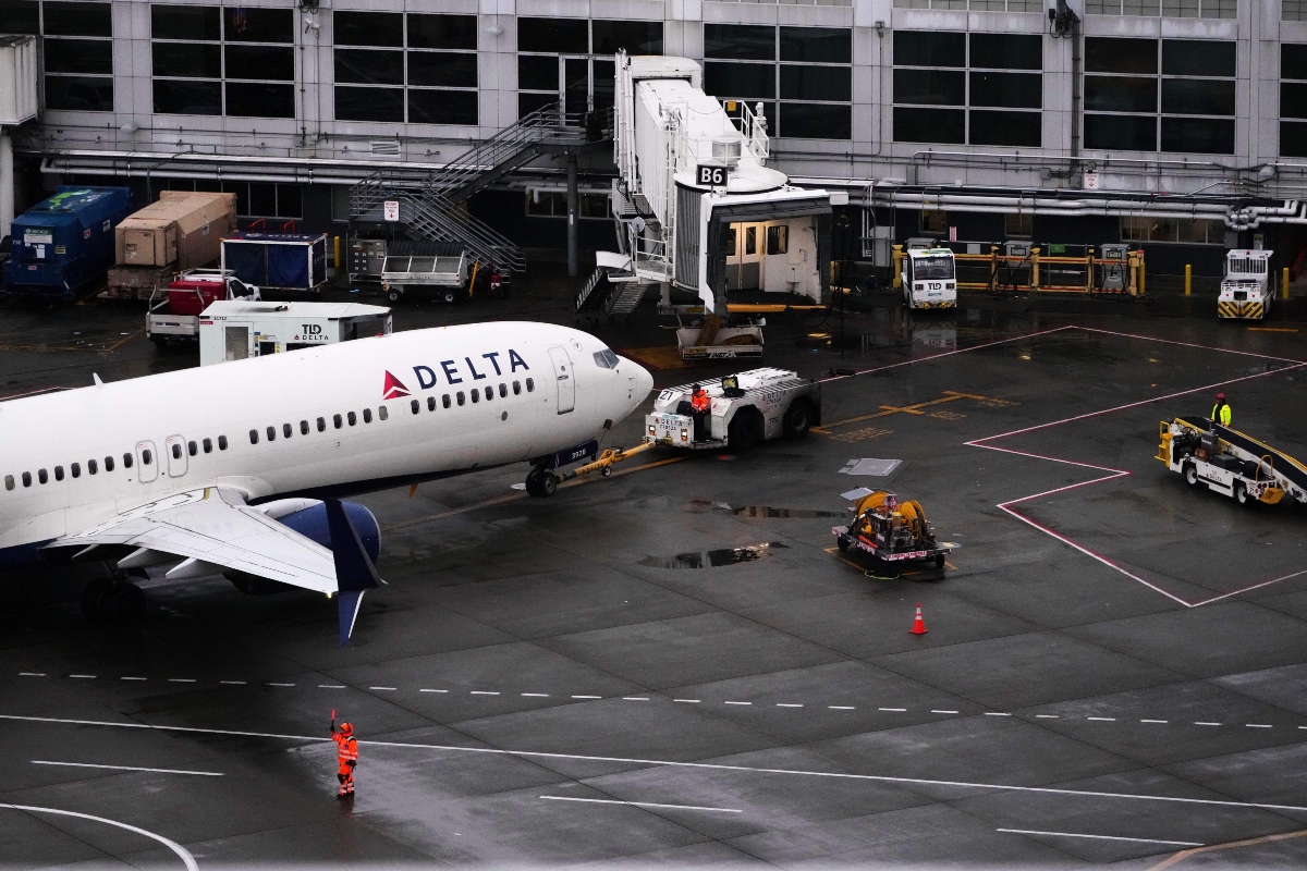 A ground crew worker signals a plane next to a Delta Airlines aircraft at Seattle-Tacoma International Airport, Thursday, Nov. 6, 2025, in SeaTac, Wash. (AP Photo/Lindsey Wasson)