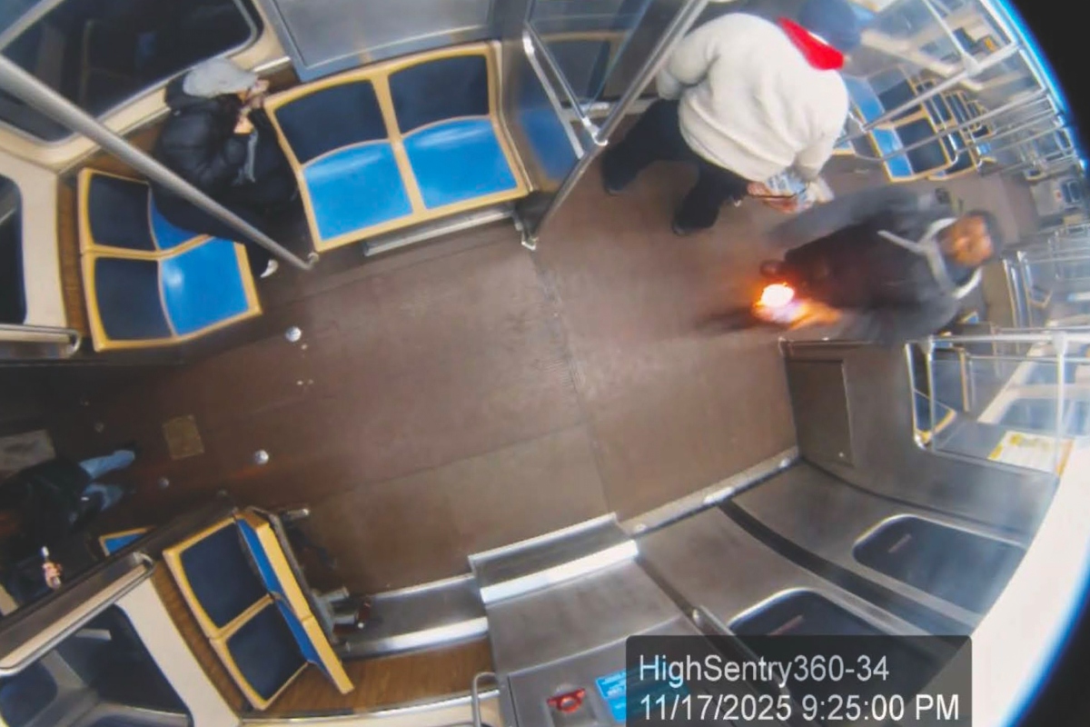 This still image taken from Chicago Transit Authority surveillance footage and included in a federal court record shows a man who federal authorities identified as Lawrence Reed holding a flaming bottle and approaching a passenger, far left, on Monday, Nov. 17, 2025, on a Chicago Blue Line train. (Chicago Transit Authority/U.S. District Court Northern District of Illinois via AP) Screenshot