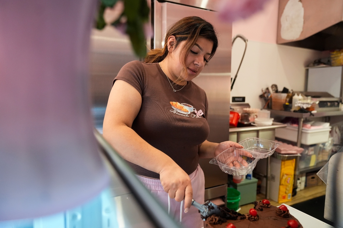 Andrea Melendez cuts a piece of cake for a customer at Pink Flores Bakery and Cafe, Wednesday, Nov. 19, 2025, in the Pilsen neighborhood of Chicago. (AP Photo/Erin Hooley)