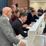 Lawmakers and Sangamon County Board members, among others, sign a beam that will be put up in the new, under-construction, Sangamon County Transportation Center.
