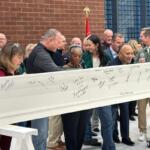 Former U.S. Rep. Rodney Davis, in green to the right in the photo, takes part in a beam signing ceremony for the new Sangamon County Transportation Center.