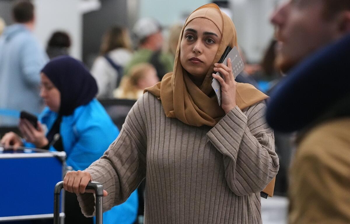 A traveler checks the status of her flight at the O'Hare International Airport in Chicago, Sunday, Nov. 30, 2025. (AP Photo/Nam Y. Huh)
