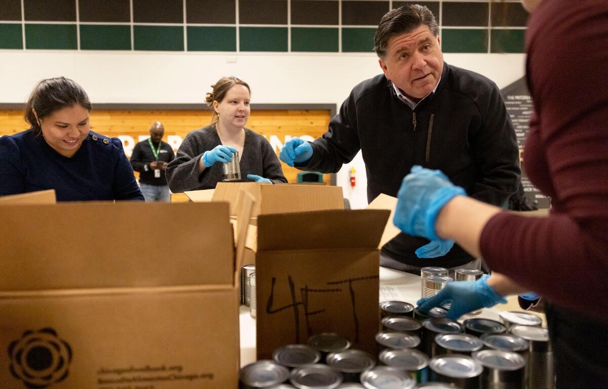 Gov. JB Pritzker packs boxes of canned goods with members of his staff while volunteering Thursday, Dec. 4, 2025, at the Greater Chicago Food Depository. (Brian Cassellav /Chicago Tribune via AP, Pool)
