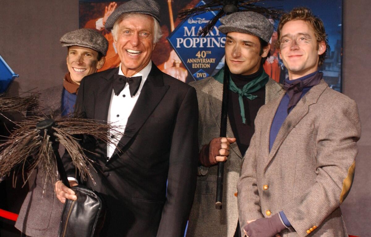 FILE - Dick Van Dyke poses with chimney sweeps during arrivals to the 40th anniversary and re-premiere of Mary Poppins at the El Capitan Theatre in Los Angeles, Tuesday, Nov. 30, 2004. (AP Photo/Ann Johansson, File)