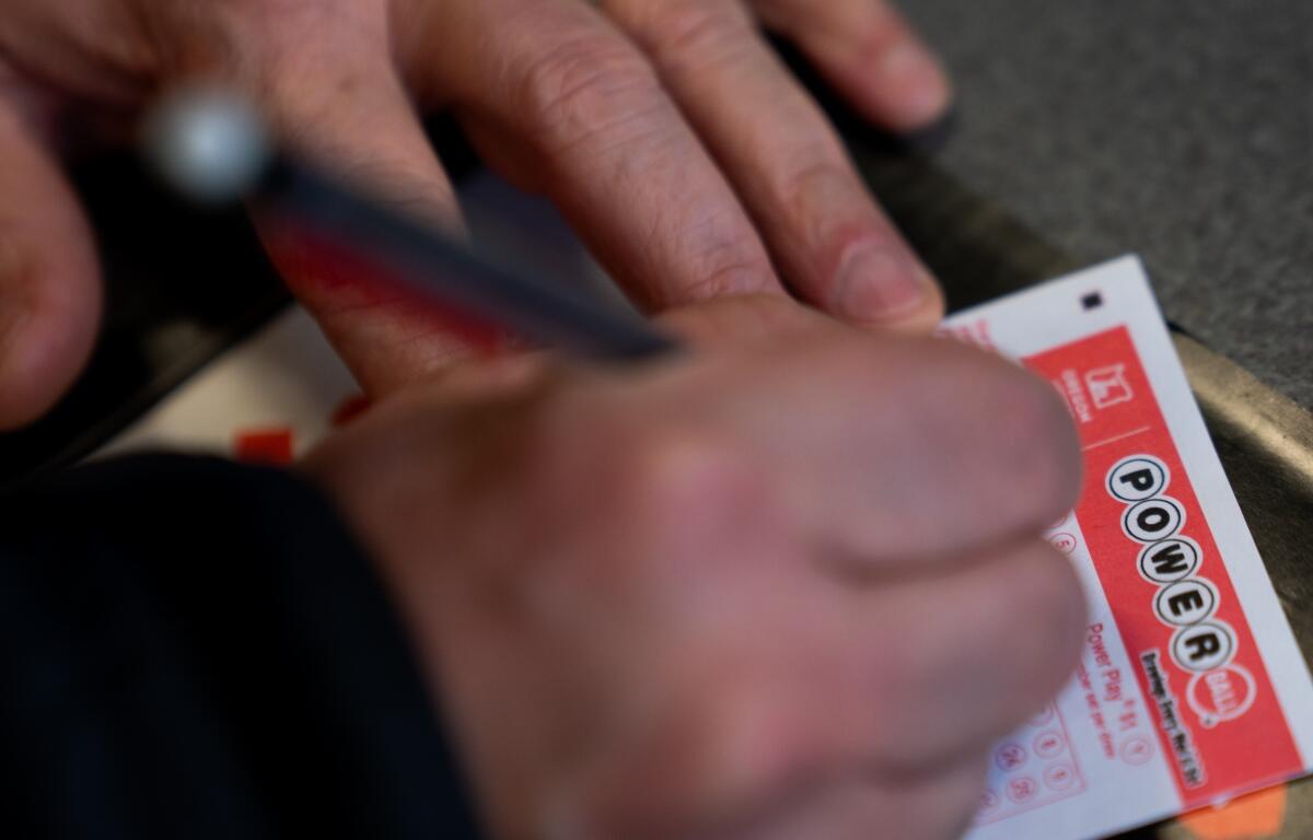 A person fills out a Powerball lottery ticket on Monday, Dec. 22, 2025, in Portland, Ore. (AP Photo/Jenny Kane)