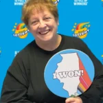 Holly of Johnston City, Illinois, celebrates with a big smile after winning a $250,000 jackpot playing the Illinois Lottery’s Magnificent Multiplier FastPlay game online.