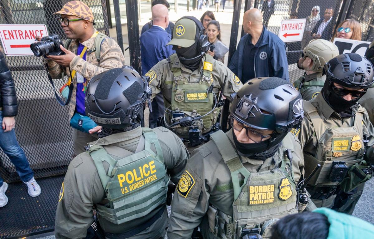 Several immigration enforcement agents push back media and protestors as U.S. Customs and Border Patrol Commander Gregory Bovino makes his way out of the federal courthouse in downtown Chicago on Oct. 28, 2025. (Capitol News Illinois photo by Andrew Adams)