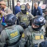 Several immigration enforcement agents push back media and protestors as U.S. Customs and Border Patrol Commander Gregory Bovino makes his way out of the federal courthouse in downtown Chicago on Oct. 28, 2025. (Capitol News Illinois photo by Andrew Adams)