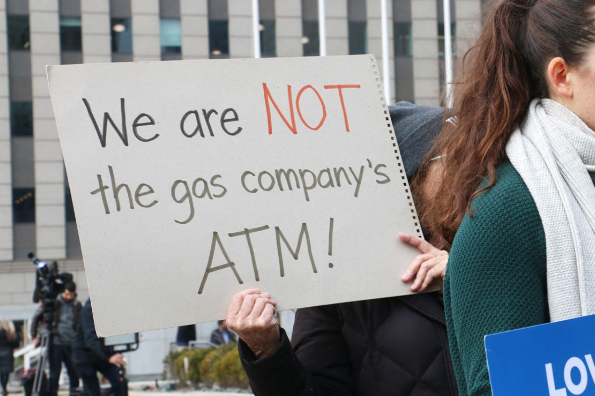 A demonstrator holds a sign reading, “We are NOT the gas company’s ATM!” at a protest held by consumer, environmental and community activists on Jan. 6, 2026. The group was criticizing Peoples Gas’ filing that sought to raise gas delivery rates in 2027. (Capitol News Illinois photo by Maggie Dougherty)