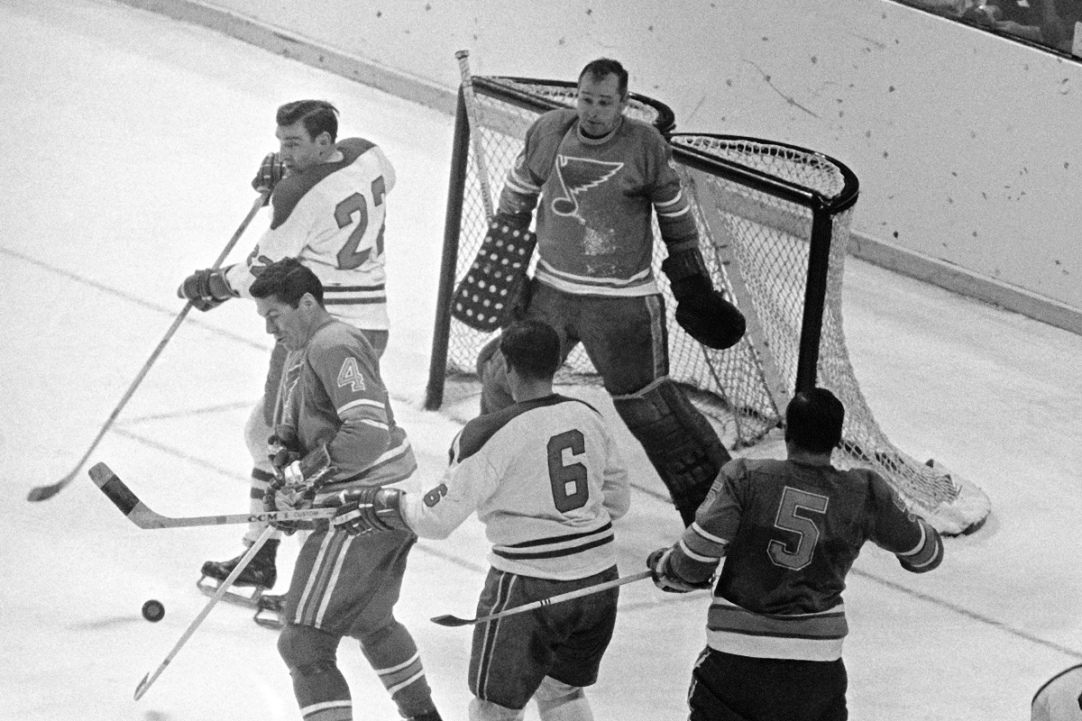 FILE - St. Louis Blues goalie Glenn Hall, top right, is pinned to his net waiting to make a save on a Montreal Canadians shot as Blues' Noel Picard (4) tries to block the puck while Canadiens' John Ferguson (22) and Ralph Backstorm wait for a rebound in the third period of their NHL hockey Stanley Cup game, May 5, 1968. (AP Photo/Fred Waters, File)