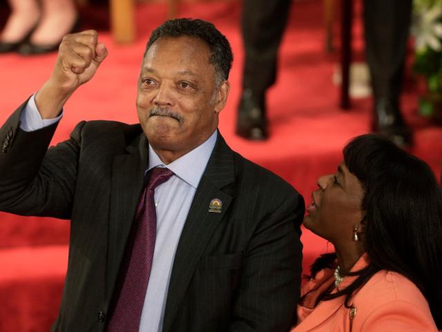 FILE - Rev. Jesse Jackson gestures to a friend in the balcony at the 16th Street Baptist Church in Birmingham, Ala., Sept. 15, 2013. The church held a ceremony honoring the memory of the four young girls who were killed by a bomb placed outside the church 50 years ago by members of the Ku Klux Klan. At right is U.S. Rep. Terri Sewell, D-Ala. (AP Photo/Dave Martin, File)