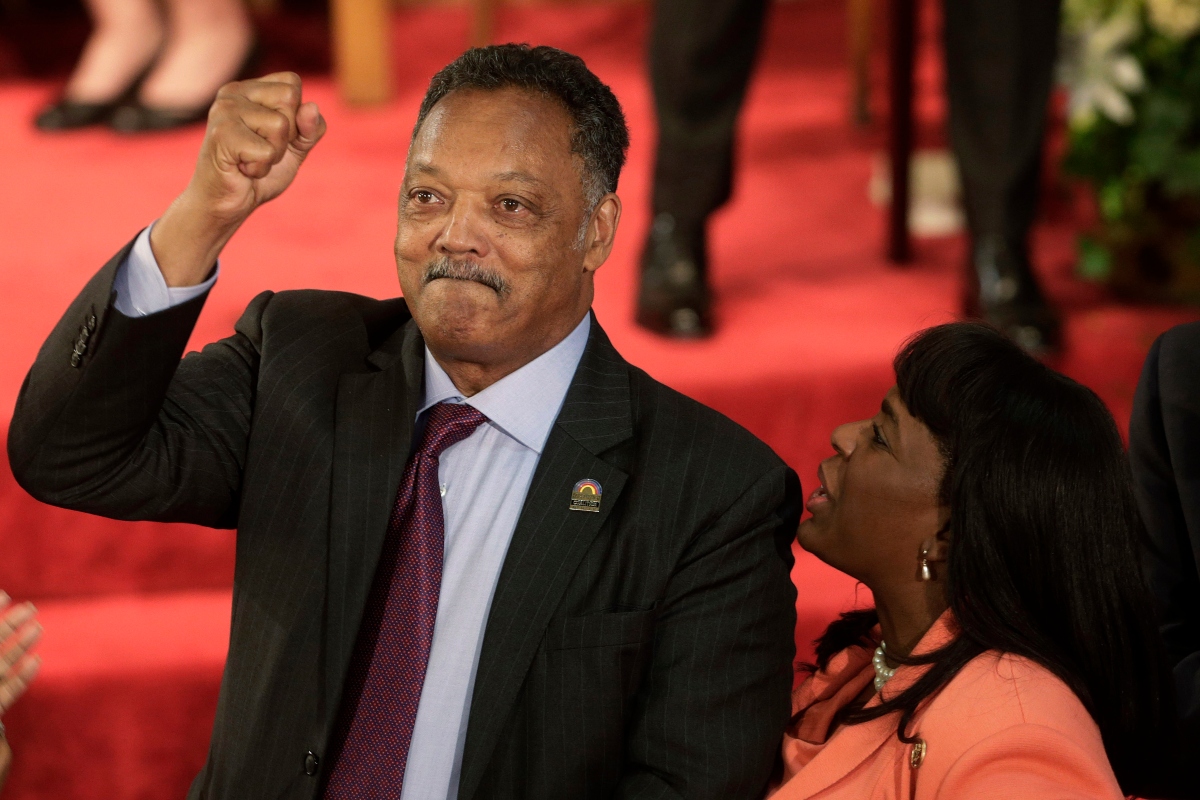 FILE - Rev. Jesse Jackson gestures to a friend in the balcony at the 16th Street Baptist Church in Birmingham, Ala., Sept. 15, 2013. The church held a ceremony honoring the memory of the four young girls who were killed by a bomb placed outside the church 50 years ago by members of the Ku Klux Klan. At right is U.S. Rep. Terri Sewell, D-Ala. (AP Photo/Dave Martin, File)