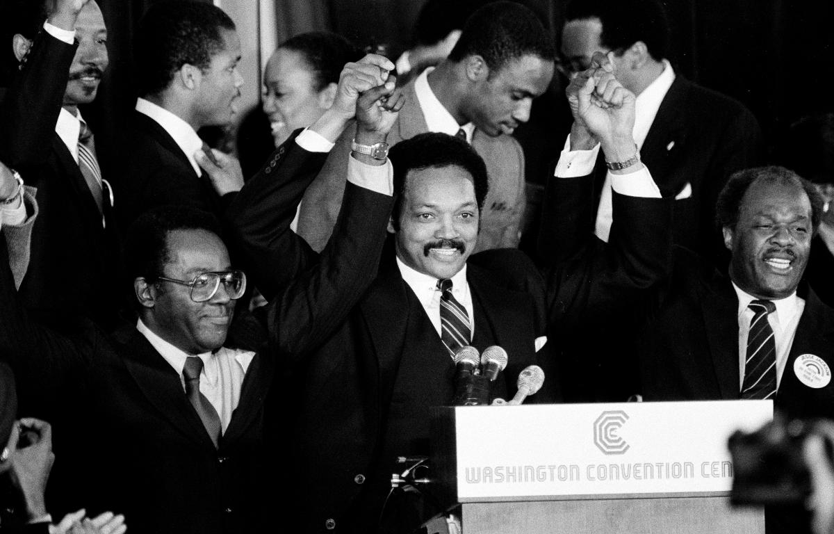 FILE - Jesse Jackson holds his hands up after announcing he will seek the Democratic nomination for president, with his campaign chairman Mayor Richard Hatcher, left, of Gary Ind., and Mayor Marion Barry of Washington, D.C., in Washington, Nov. 3, 1983. (AP Photo/Scott Stewart, File)
